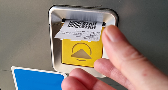 Hand entnimmt Ticket aus Automaten